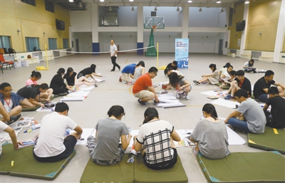 2015年7月14日，在北京一師附小地下體育館內(nèi)，2015新京報(bào)第八屆大學(xué)生名企實(shí)習(xí)學(xué)員在參加實(shí)習(xí)培訓(xùn)，在老師的指引下，通過(guò)裁剪雜志上的圖片，拼組自己的海報(bào)。